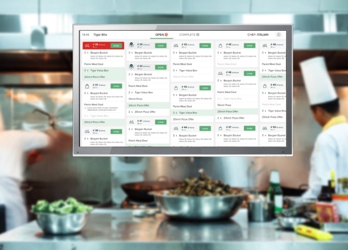 Restaurant kitchen team working with a digital order-management display